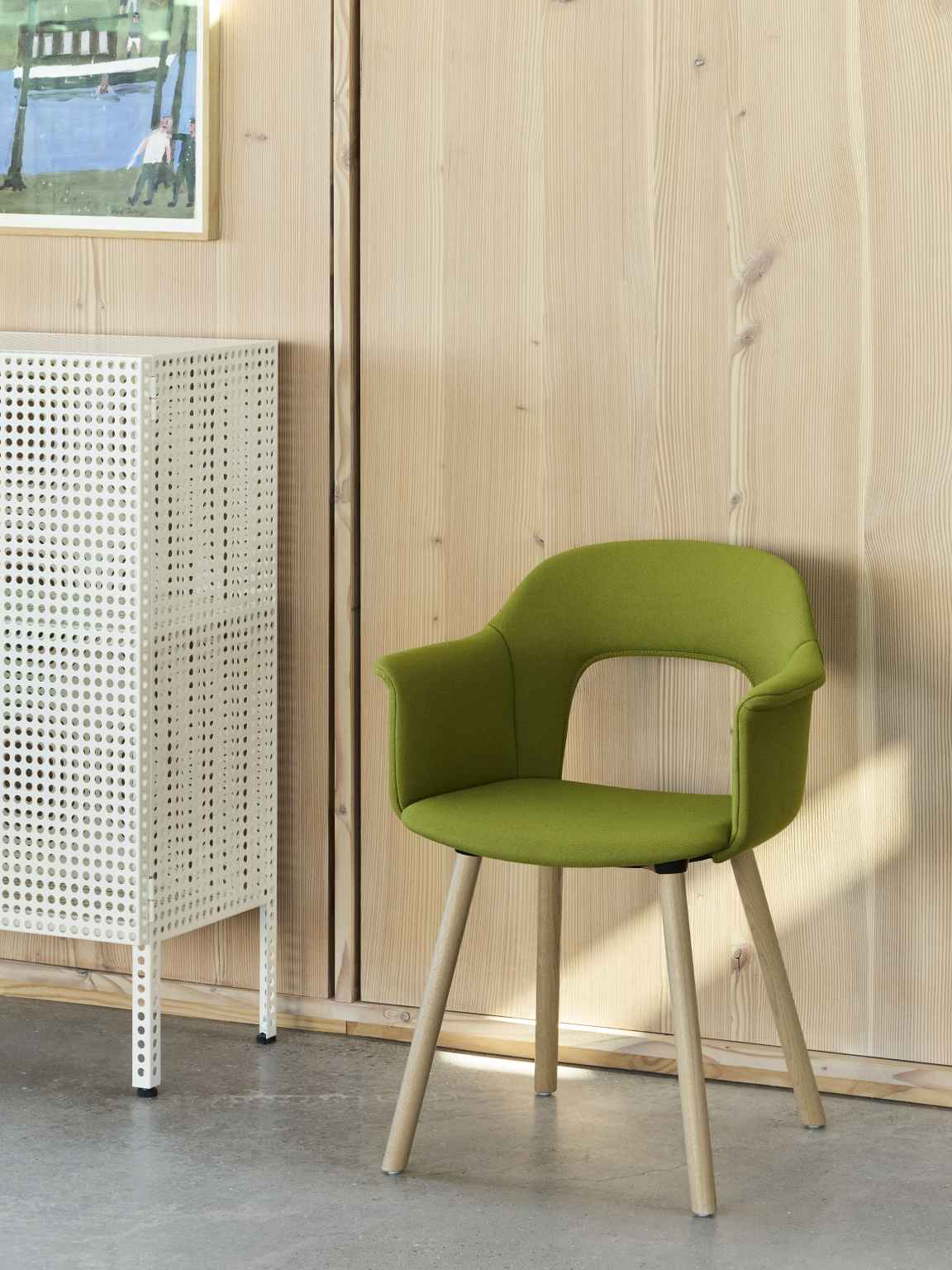 Grüner Hay Layout Armchair 224 Armlehnstuhl mit Holzbeinen vor einer Holzwand und einem weißen Schrank.