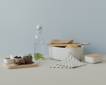 Produktfoto: Brotkasten mit Holzdeckel, Wasserflasche, Schälchen mit Snacks und Topflappen in neutralen Farben.
