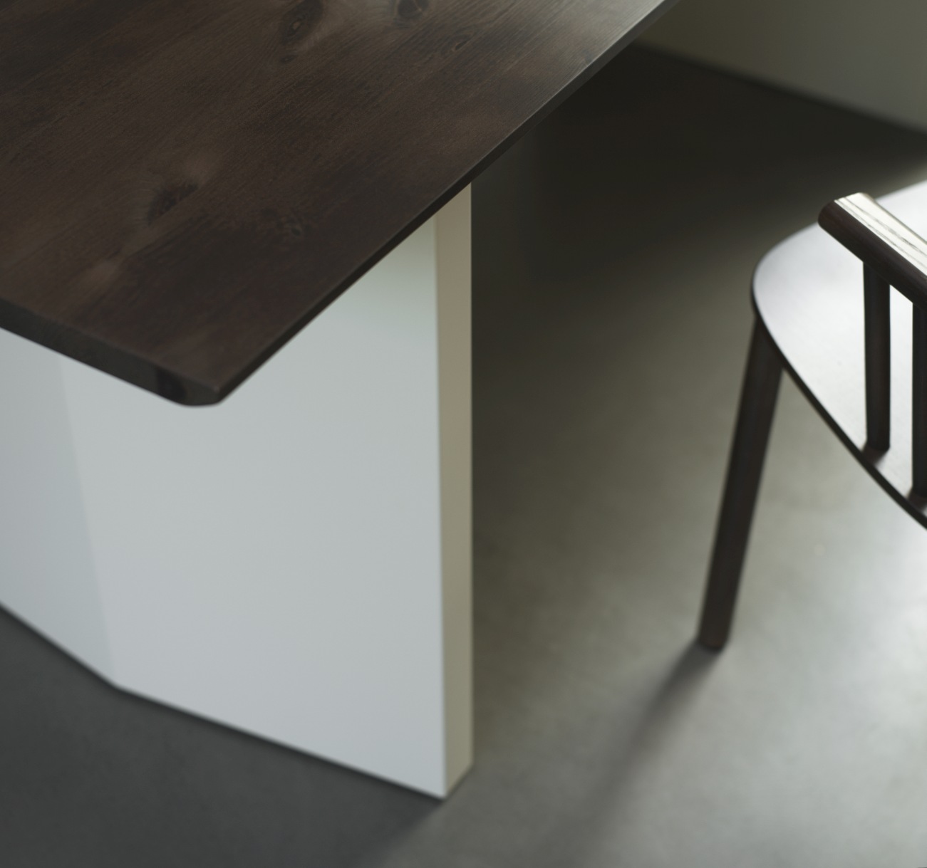Detailaufnahme: Normann Copenhagen Panel Tisch, Esstisch mit dunkler Holzplatte und weißem Untergestell, Stuhl im Hintergrund.