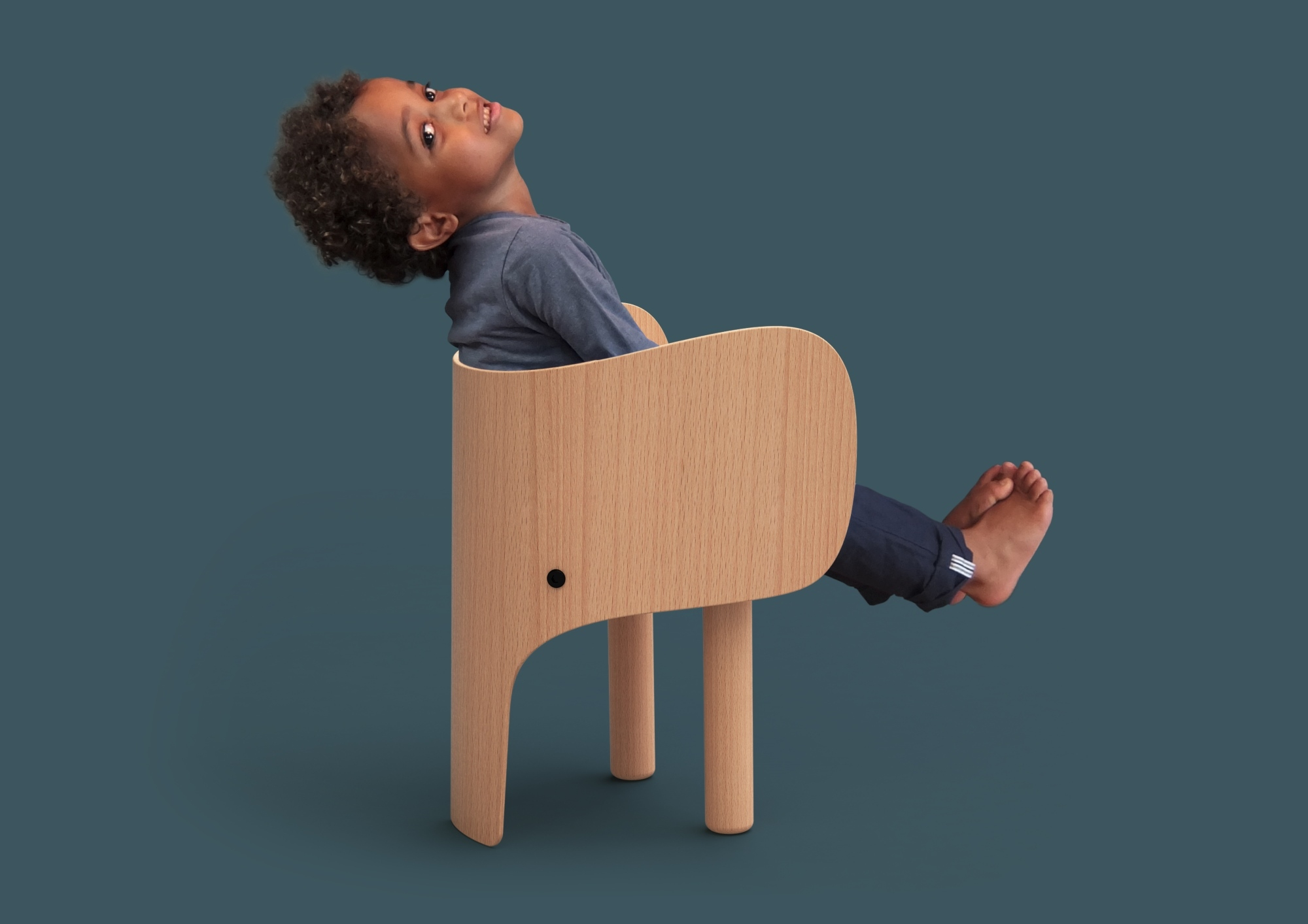 Junge sitzt entspannt im EO Elephant Chair Kinderstuhl aus Holz, Blick nach oben.