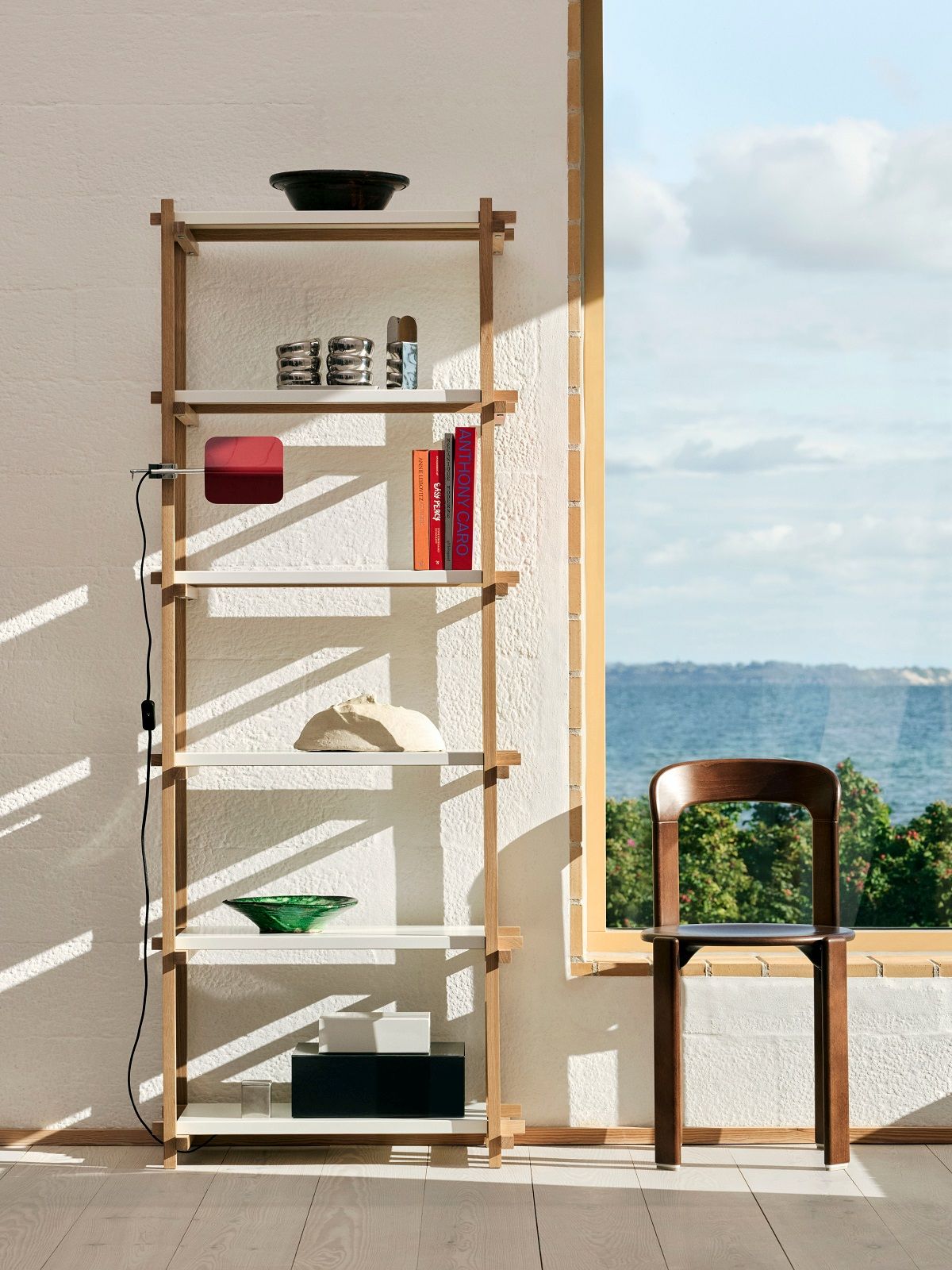 Helles Interieur mit hohem Woody Shelving Regal von Hay, dekoriert mit Büchern und Deko-Objekten.