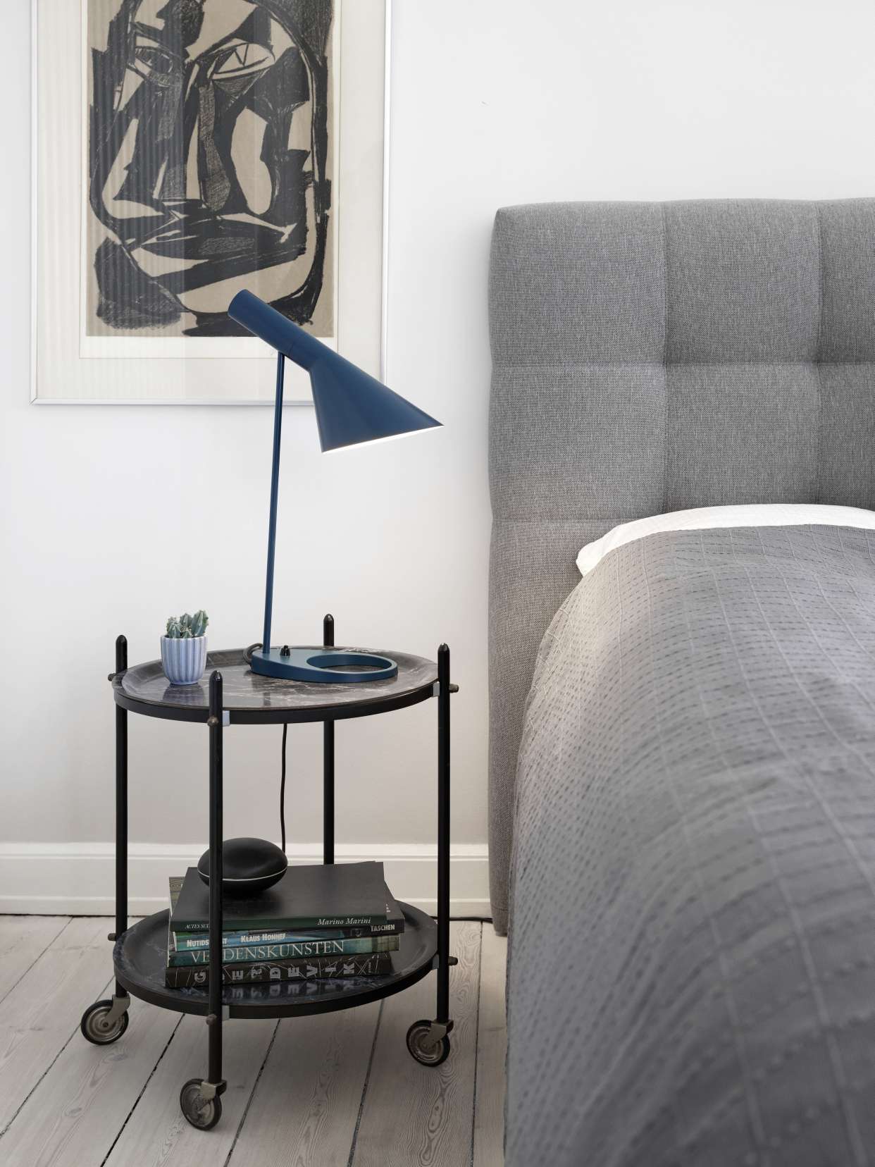 AJ Tischleuchte von Louis Poulsen in Blau auf Nachttisch neben Bett. Design Lampe.