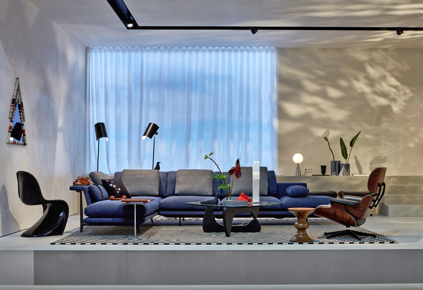 Schwarzer Panton Chair von Vitra in modernem Wohnzimmer mit blauem Sofa und Designermöbeln.