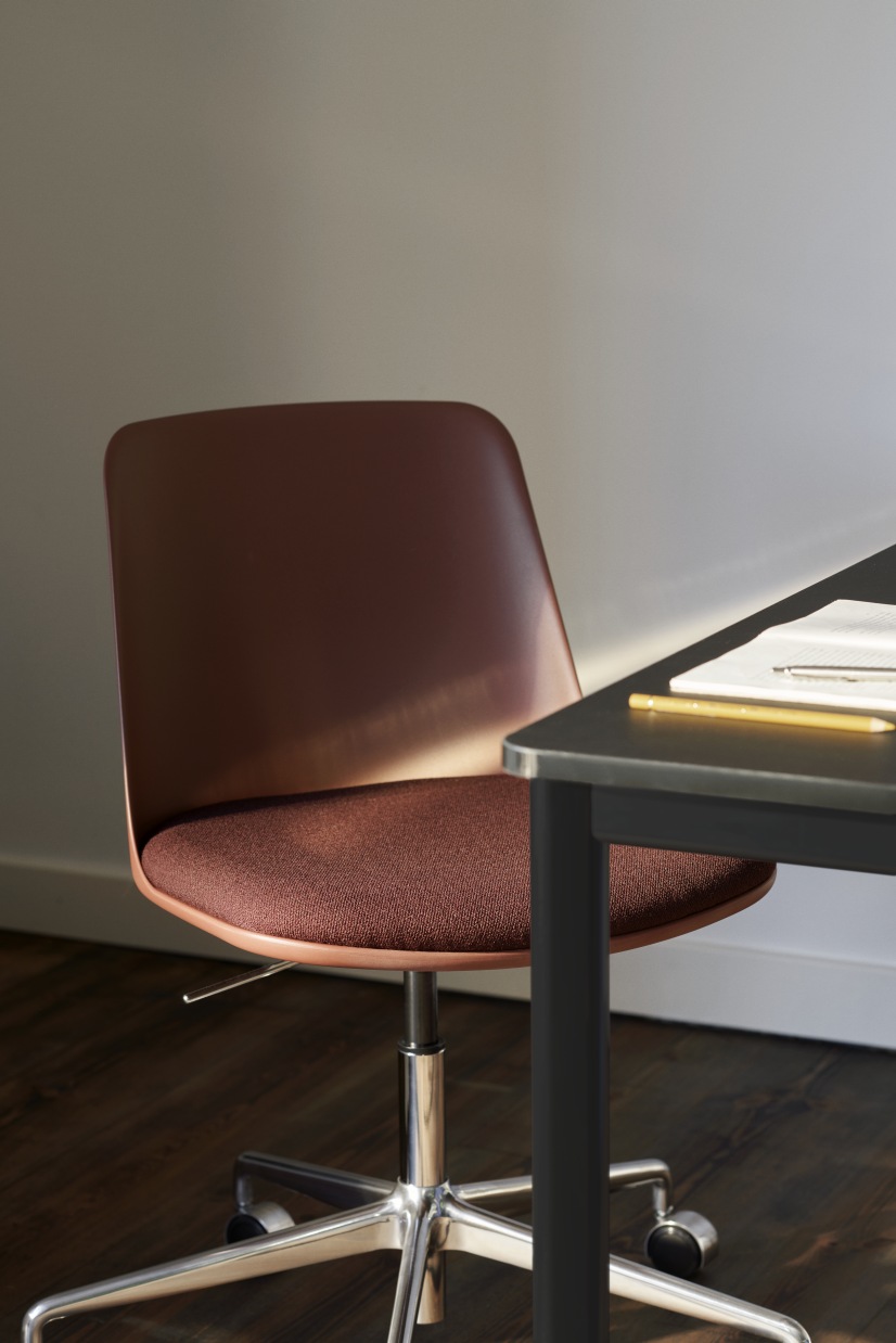 Detailaufnahme von AndTradition Drip Table HW58 mit braunem Bürostuhl und Notizbuch auf dunkler Tischplatte.