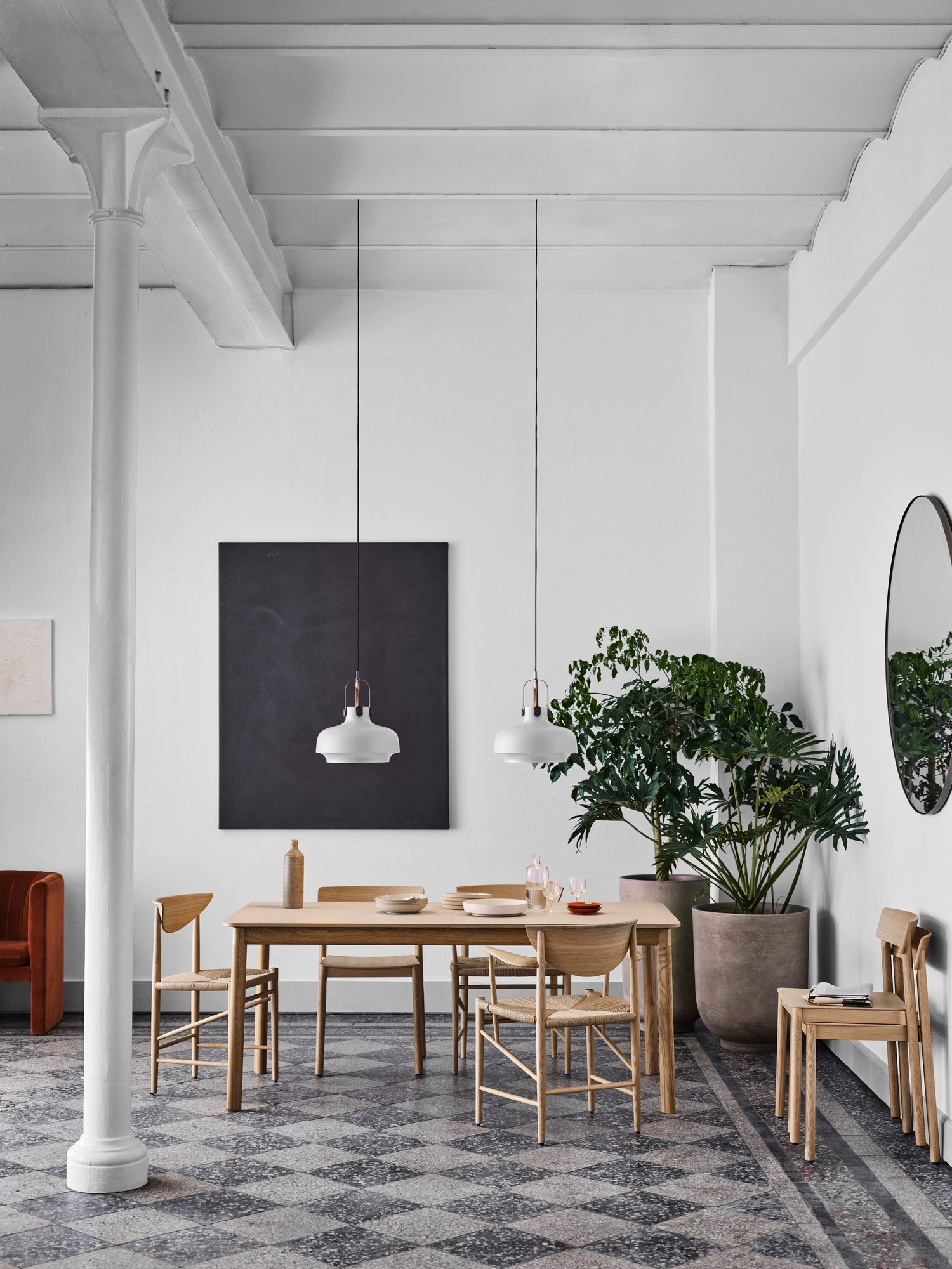 Helle Esszimmerszene mit Copenhagen SC7 Pendelleuchten von AndTradition über einem Esstisch mit Holzstühlen.