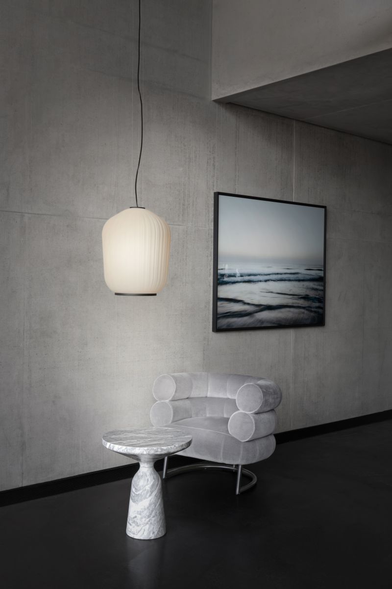 Bell Beistelltisch aus Marmor mit grauem Sessel und Lampe in modernem Wohnraum.