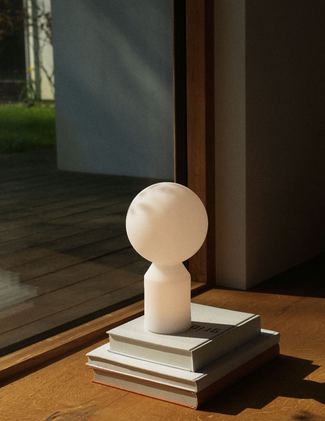 Nahaufnahme der Yo Lamp Small Tischleuchte von Normann Copenhagen, stehend auf einem Bücherstapel.