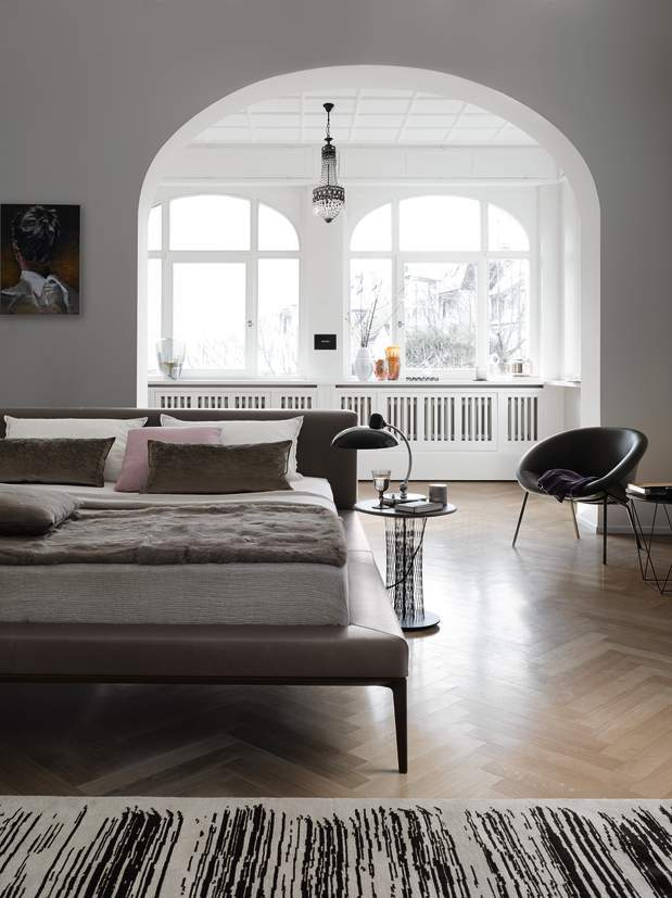 Moderner Wohnraum mit Walter Knoll Sessel 369, Bett, Lampe und Teppich auf Parkettboden.