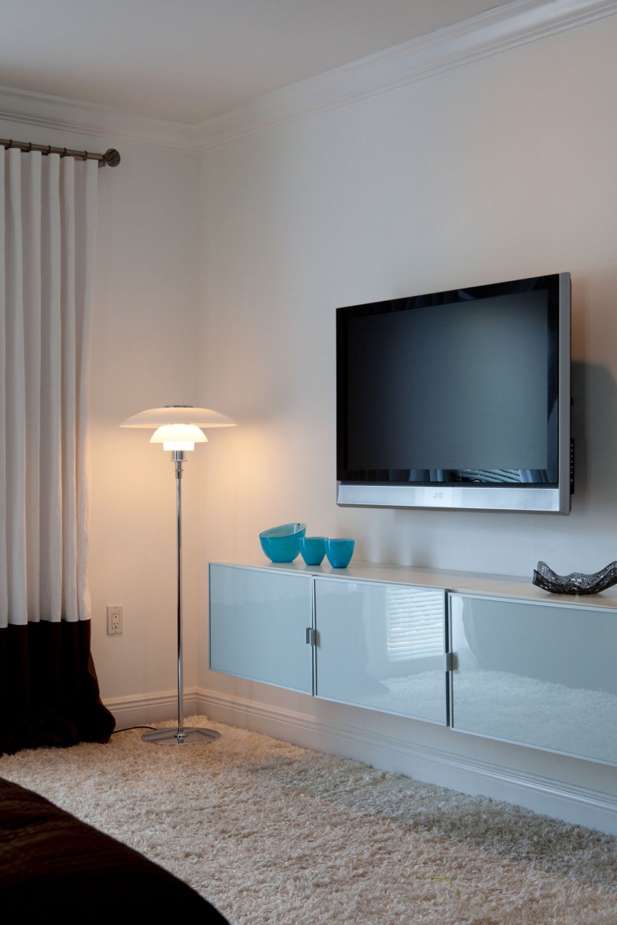 Modernes Wohnzimmer mit TV, Stehlampe, weißen Hochglanzmöbeln und flauschigem Teppich für stilvolles Interieur.