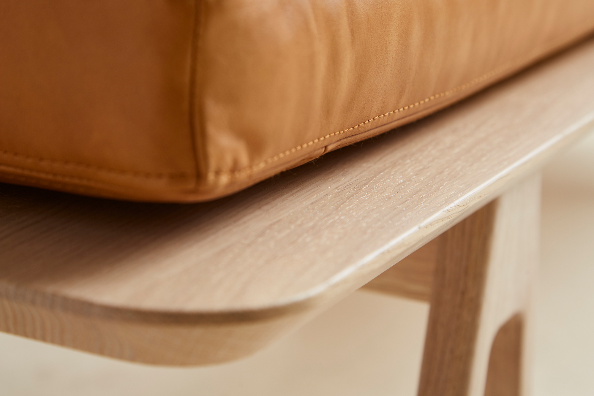Detailaufnahme Level Daybed Liege von Woud: Cognacfarbenes Lederkissen auf hellem Eichenholzgestell.