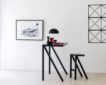 Schwarzer Stehtisch mit Barhocker im minimalistischen Design, dekoriert mit Lampe und Vasen, moderne Inneneinrichtung.