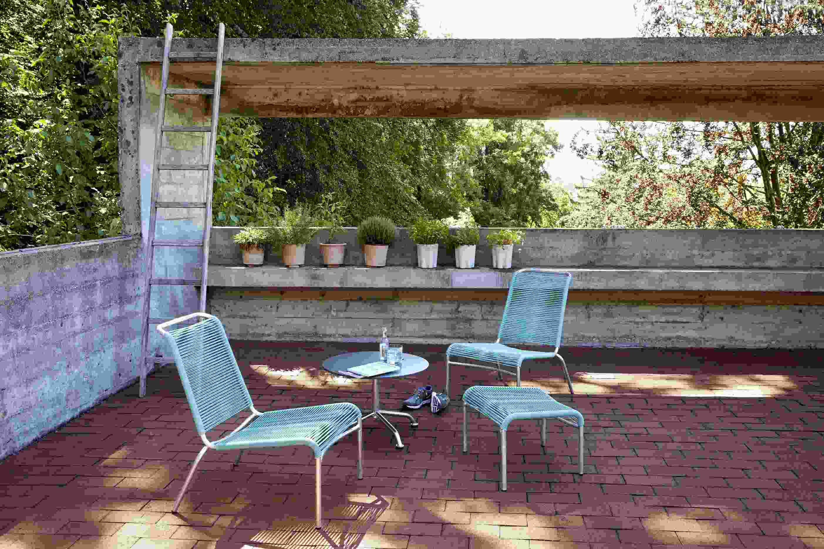 Altorfer Lounge Hocker Outdoor Embru Lichtgrün auf Terrasse mit Stühlen und Tisch.