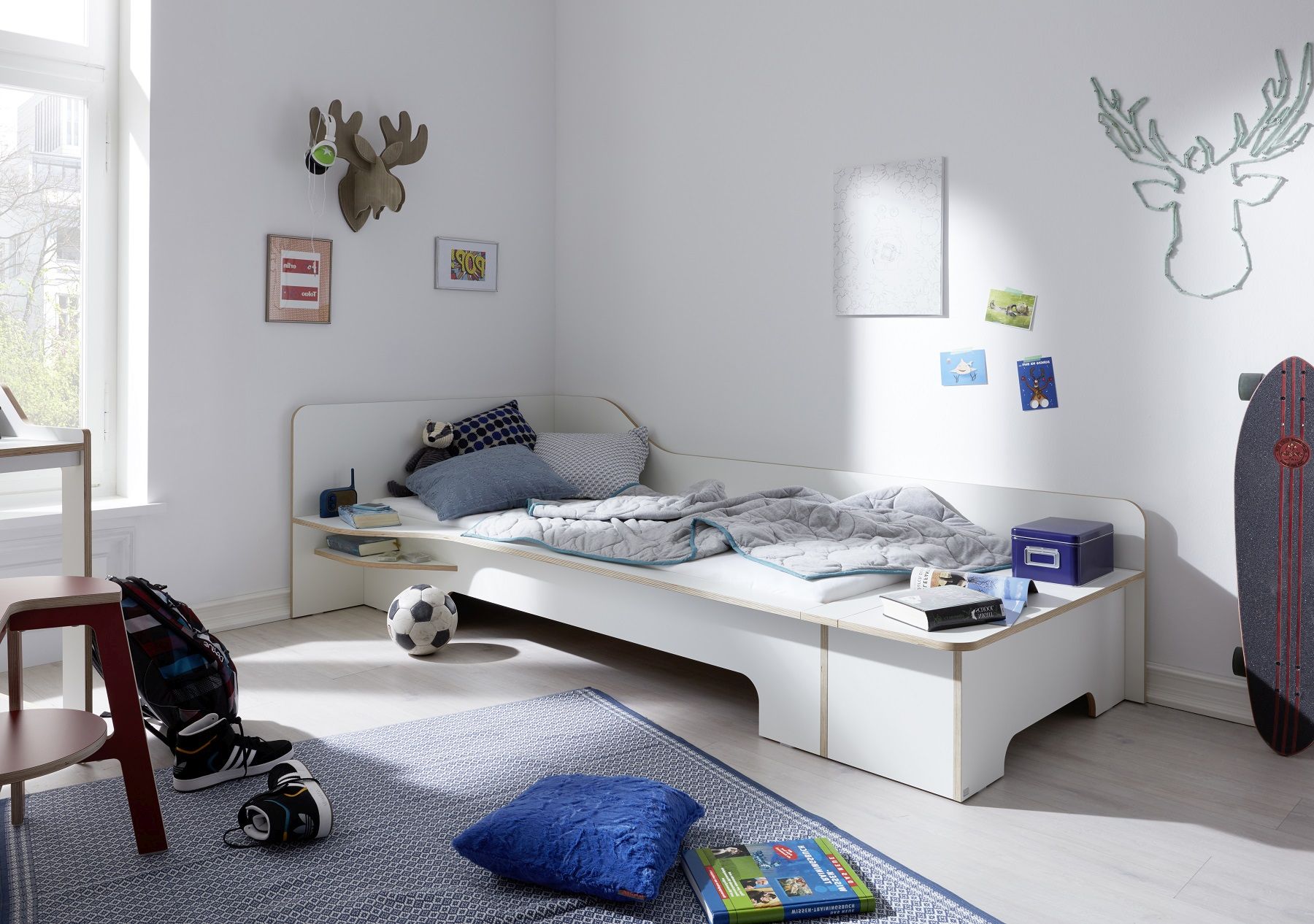 Helles Jungenzimmer mit Plane Einzelbett von Müller Möbelwerkstätten, inklusive Bettwäsche, Teppich, Fußball und Skateboard.