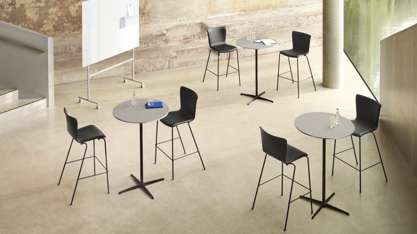 Mehrere graue Zirkular Stehtische von Fritz Hansen mit schwarzen Barhockern in einem modernen Büroraum.