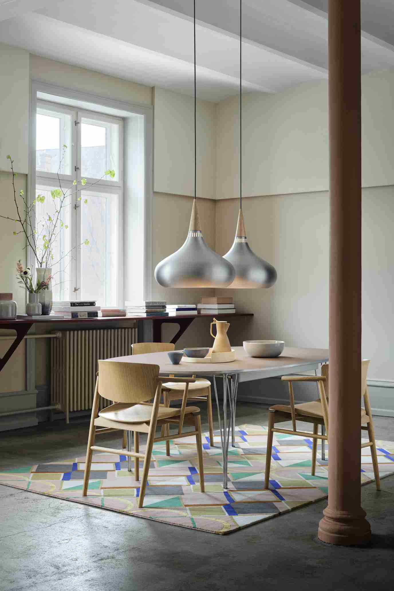 Esszimmer mit Super Elliptisch Tisch von Fritz Hansen, Holzstühlen und zwei silbernen Hängeleuchten.