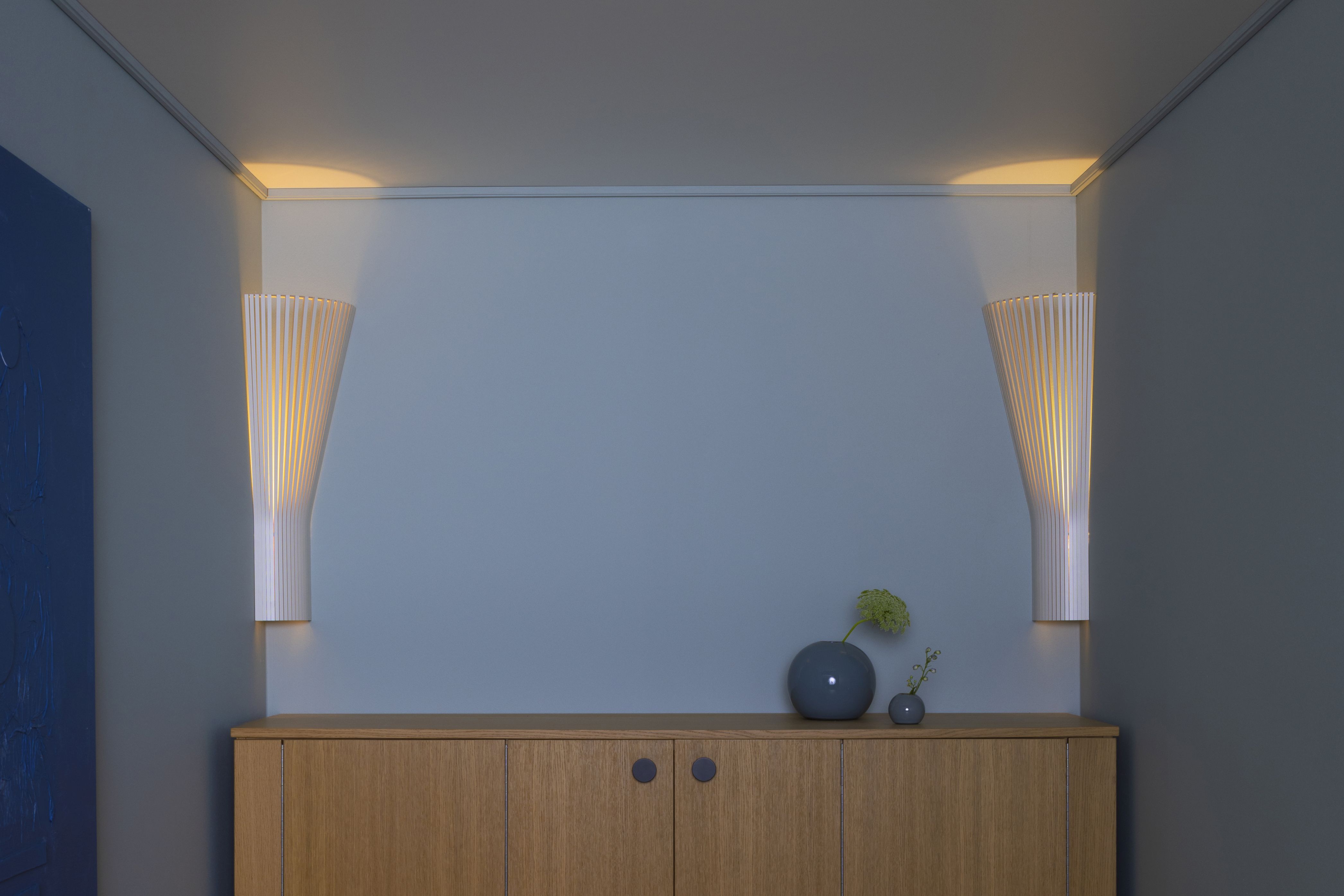 Secto 4236 Eckleuchte von Secto Design, zwei skandinavische Designleuchten aus Holz an einer blauen Wand.