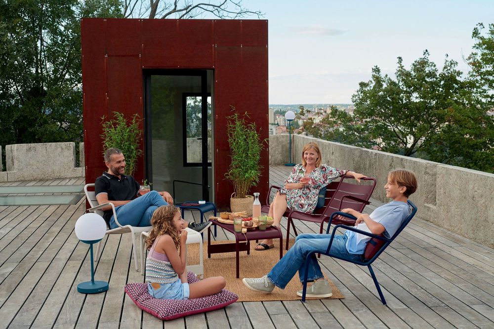 Familie entspannt auf der Terrasse mit Fermob Luxembourg Sesseln und Outdoor-Möbeln.