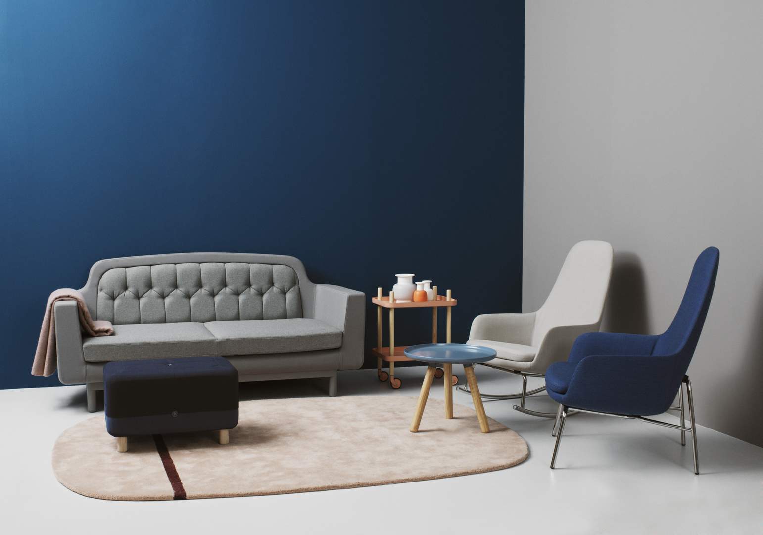 Wohnzimmer-Szene mit Normann Copenhagen Era Lounge Sessel hoch in Blau und Grau, Sofa und Teppich.
