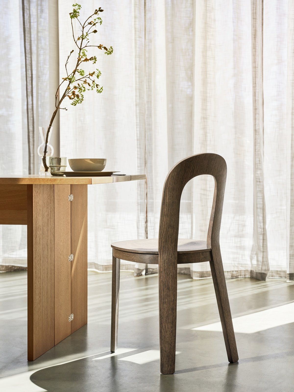Esstisch aus Holz mit Stuhl und Dekoration vor hellem Vorhang, Möbel für Esszimmer.