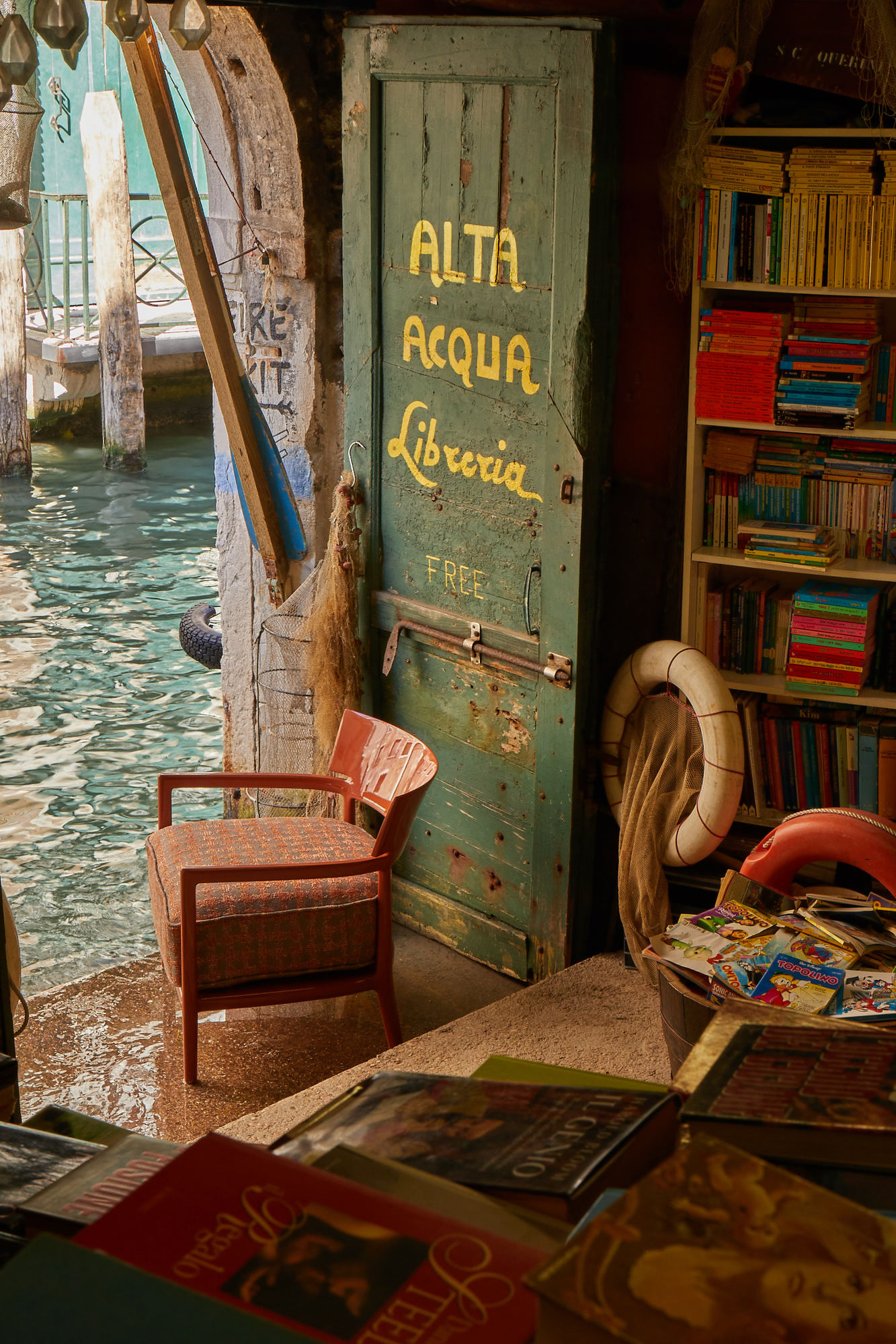 Cara Sessel von Kartell vor einer Buchhandlung in Venedig, Italien, mit Wasser im Vordergrund.