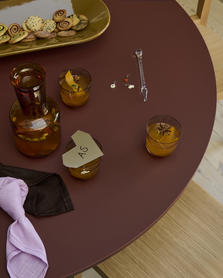 Nahaufnahme des Muuto MIDST Table Esstisches in Pflaume, gedeckt mit Getränken, Gebäck und Servietten.