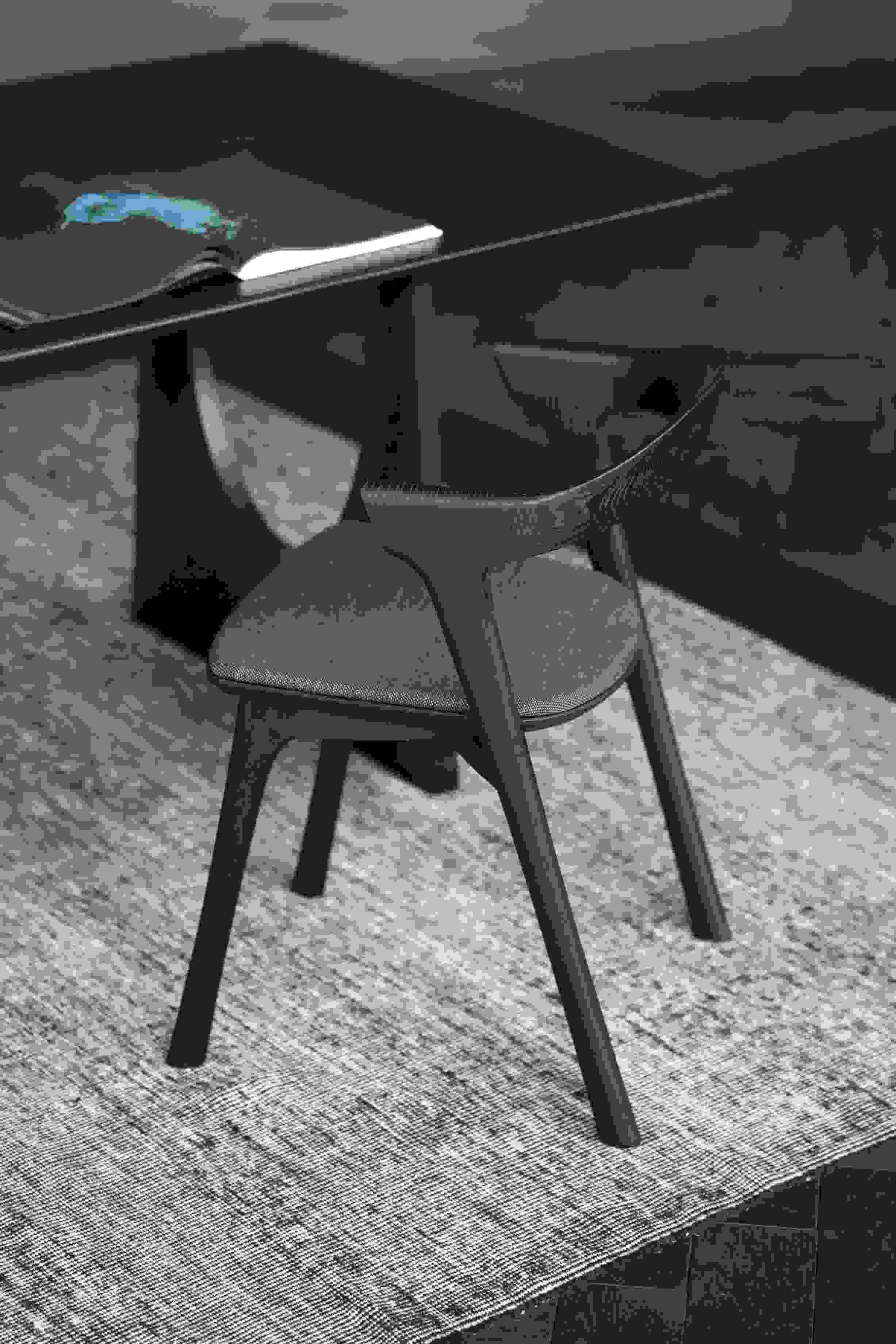 Nahaufnahme des Bok Stuhls von Ethnicraft, braunes Eichenholz mit schwarzem Stoffbezug, minimalistisches Design.