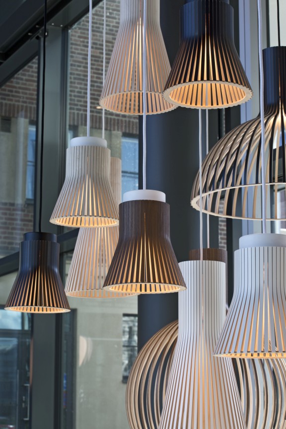 Nahaufnahme verschiedener Secto Design Pendelleuchten aus Holz in Weiß, Birke und Schwarz.