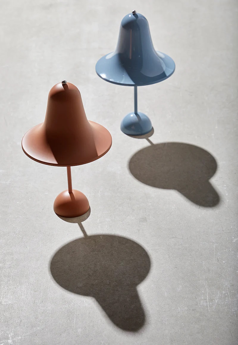 Zwei Pantop Tischleuchten: eine hellblaue und eine terrakottafarbene Designlampe auf einem grauen Untergrund.