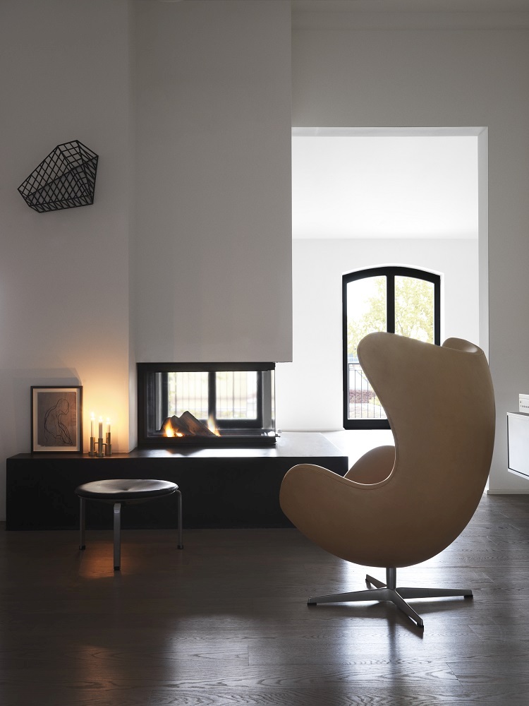 Beiger Sessel und PK33 Hocker von Fritz Hansen vor modernem Kamin in minimalistischem Wohnzimmer.