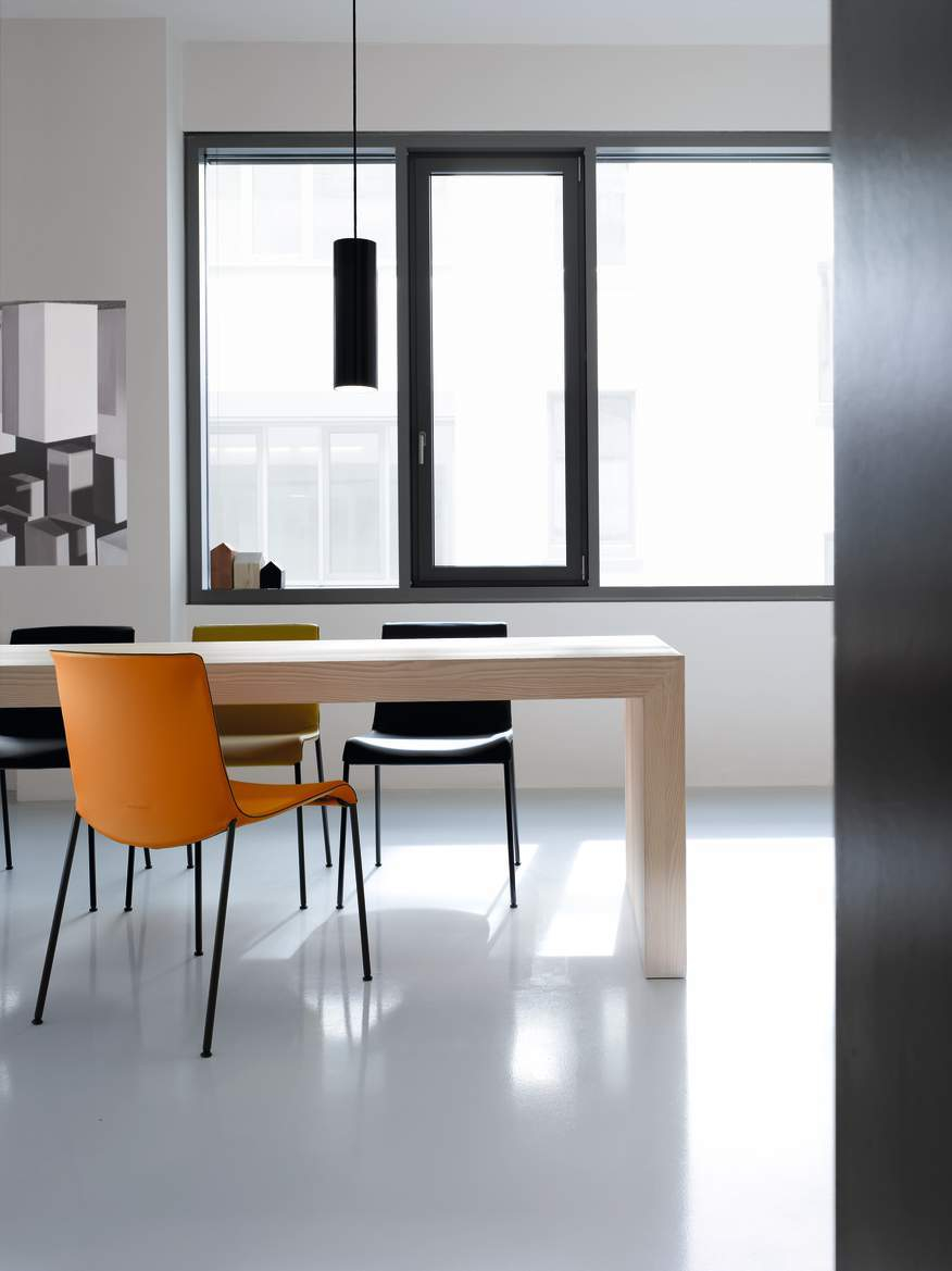 Esszimmer mit Esstisch und mehreren Liz Stühlen von Walter Koll in Orange, Schwarz und Gelb.