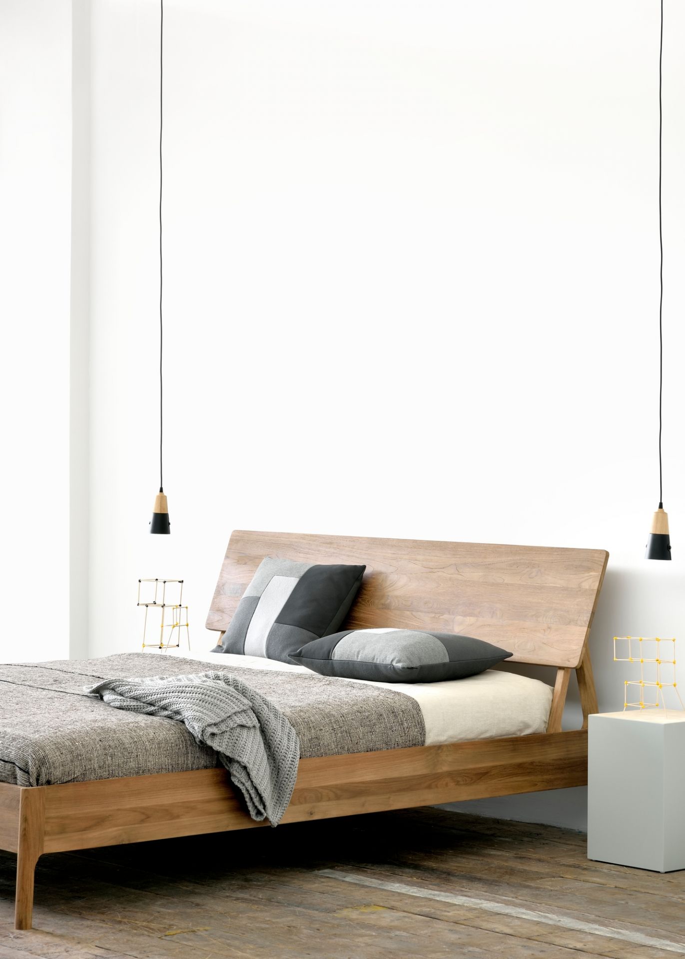Holzbett mit grauer Tagesdecke und Kissen, Nachttischlampe und minimalistischer Dekoration für Schlafzimmer Design.