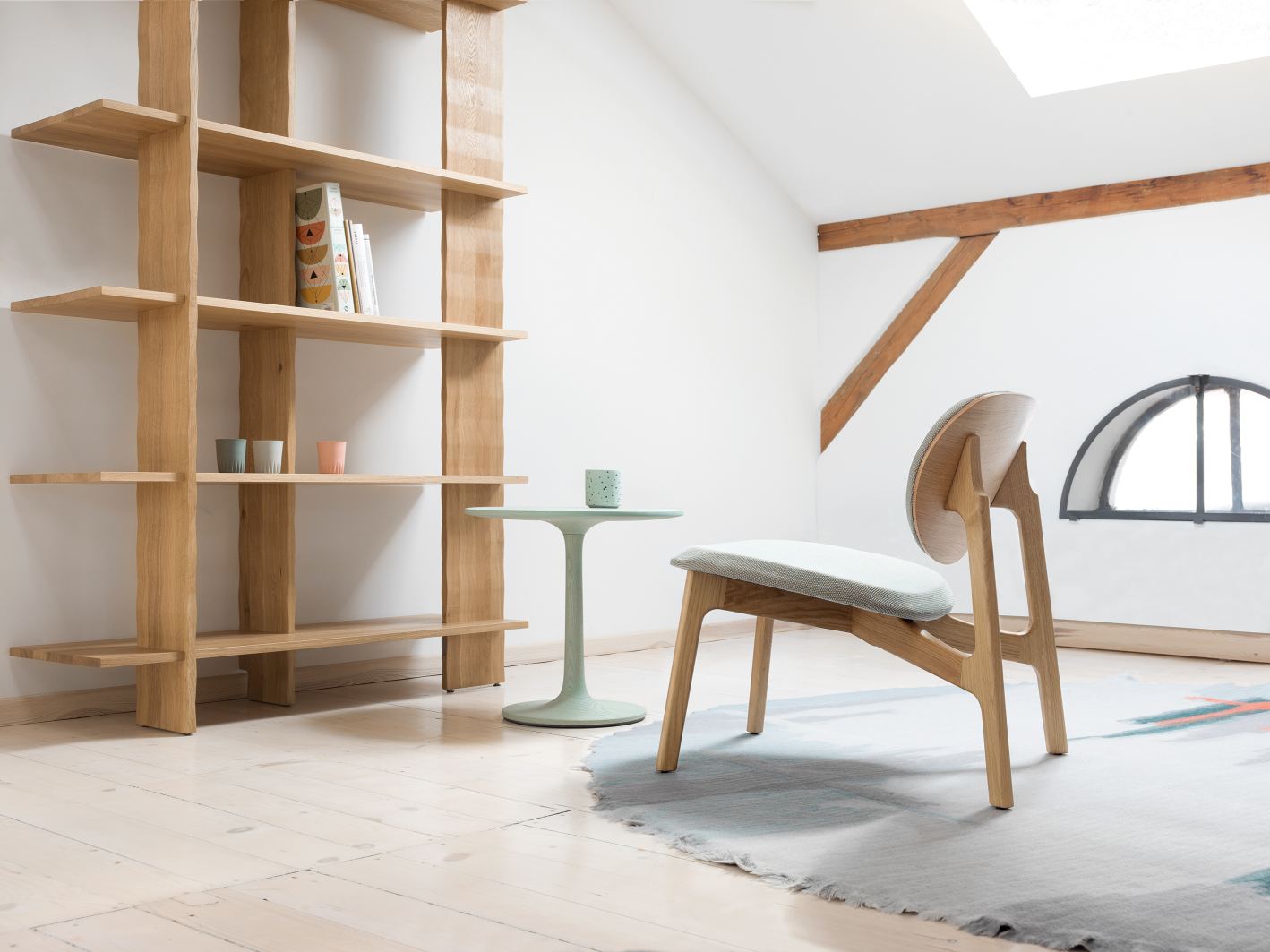 Turntable Couch Beistelltisch im Raum mit Holzregal, Stuhl und Teppich in hellem Interieur.