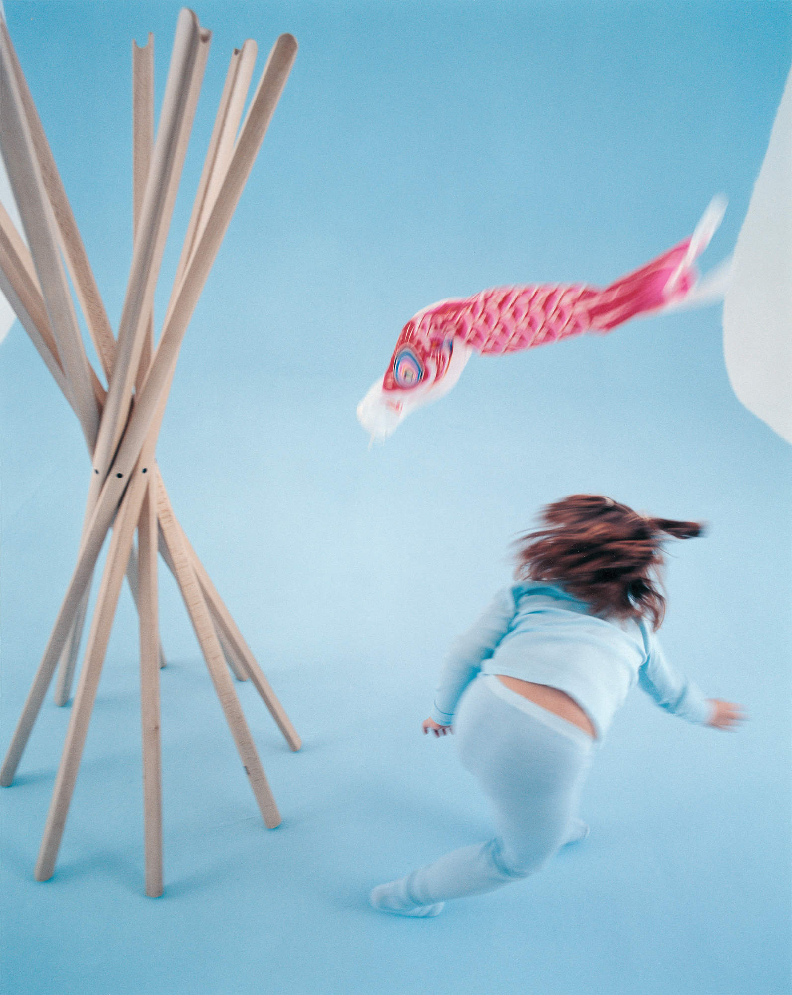 Sciangai Kleiderständer von Zanotta aus hellem Holz, mit Kind und japanischer Koinobori-Flagge im Hintergrund.