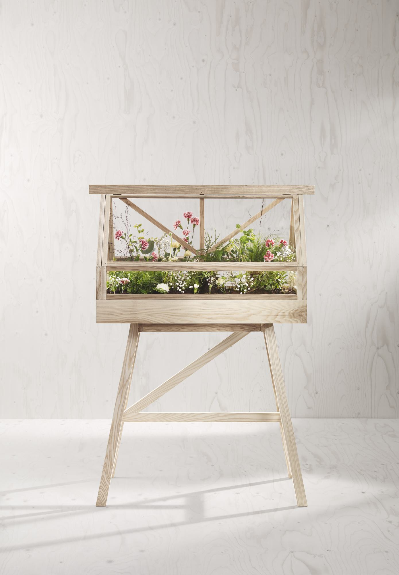 Helles Holz-Pflanzgefäß mit Glasabdeckung und Blumen auf einem passenden Holzgestell. Zimmergewächshaus für Pflanzen.