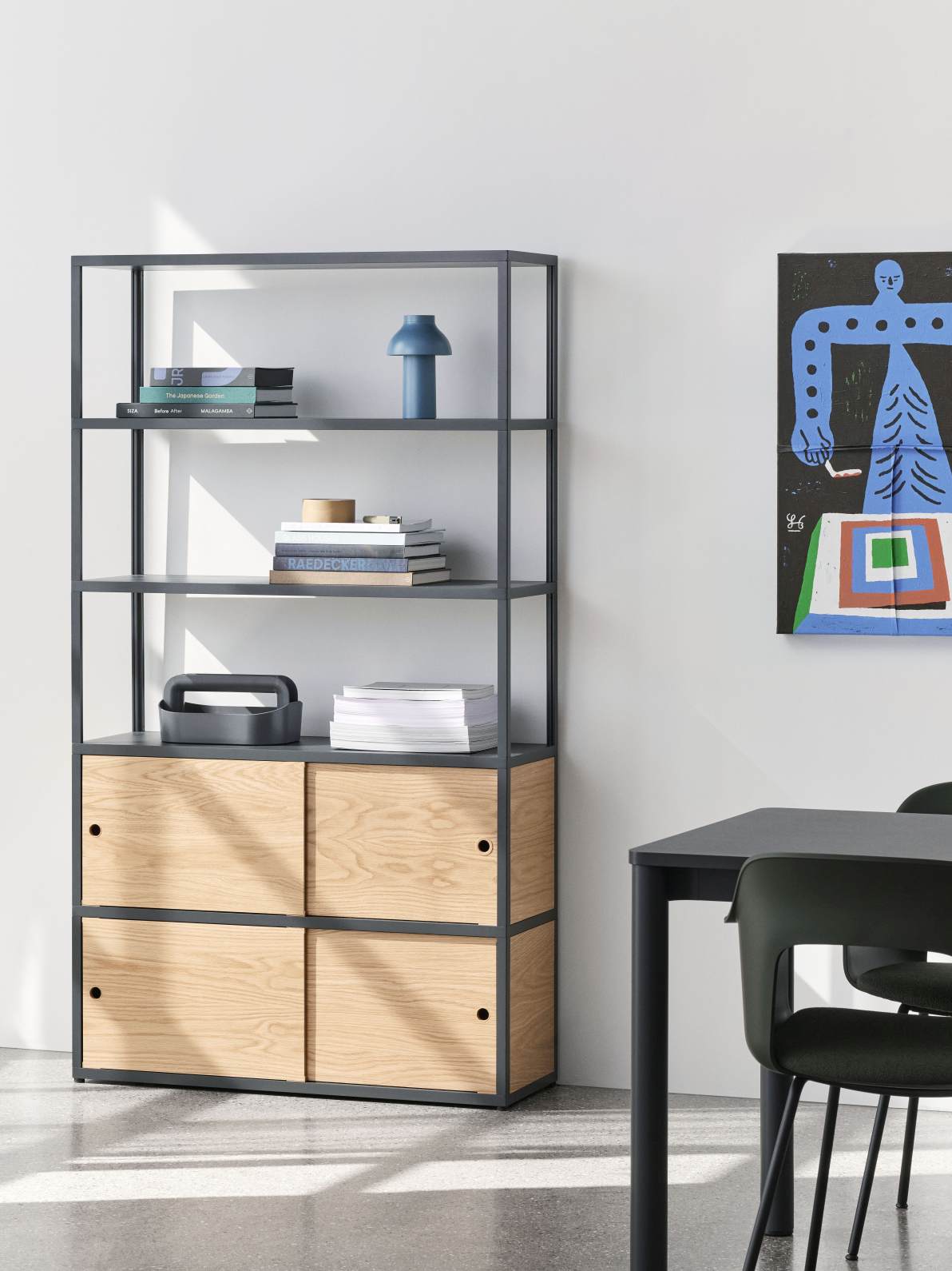 Annex Regal mit Holzschiebetüren und Hay Esstisch im modernen Wohnraum, Bücher und Dekoration auf den Regalen.