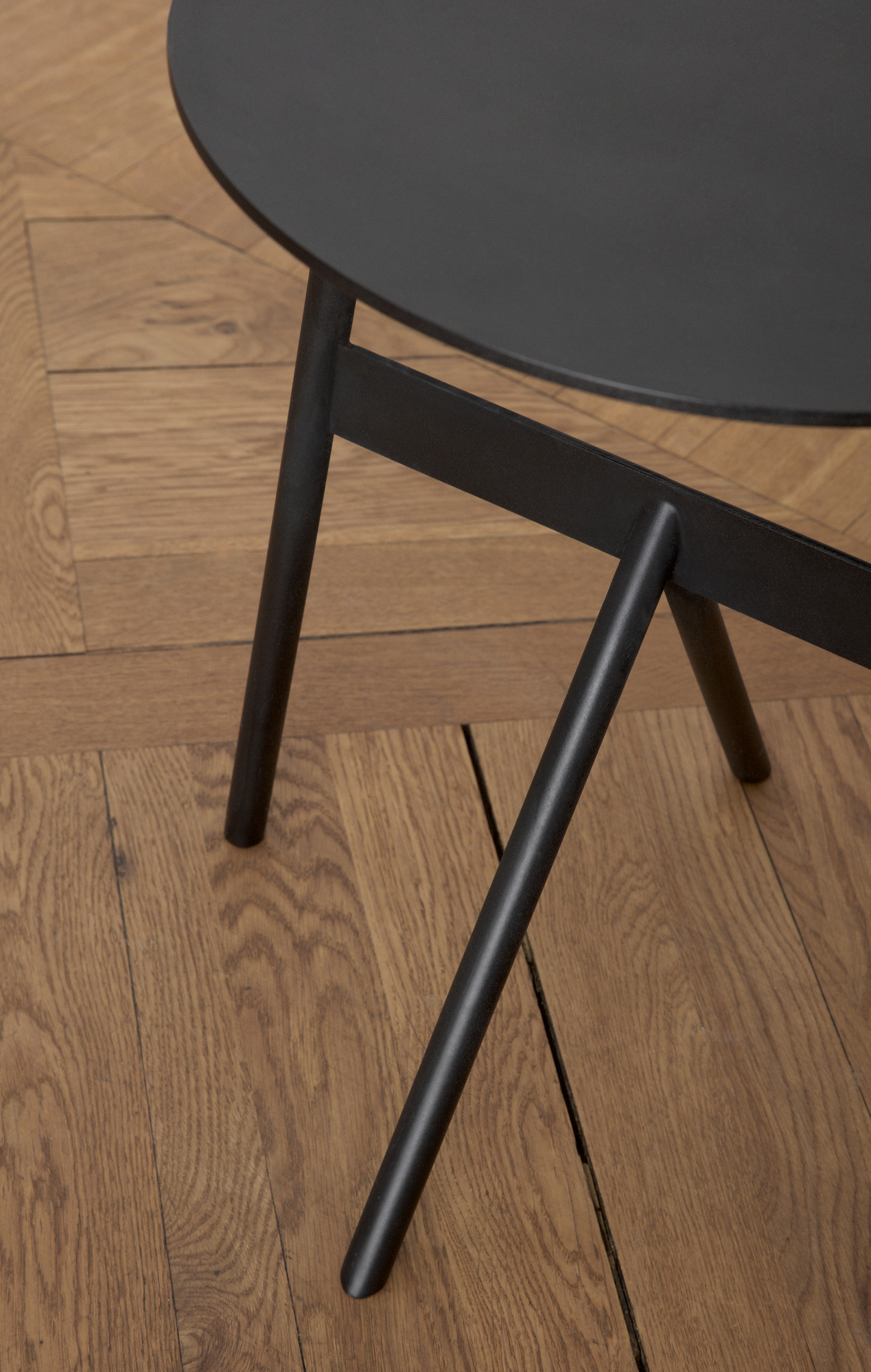 Detailaufnahme vom Normann Copenhagen Stock Table Beistelltisch in Schwarz auf einem Holzboden. Moderner, runder Couchtisch.