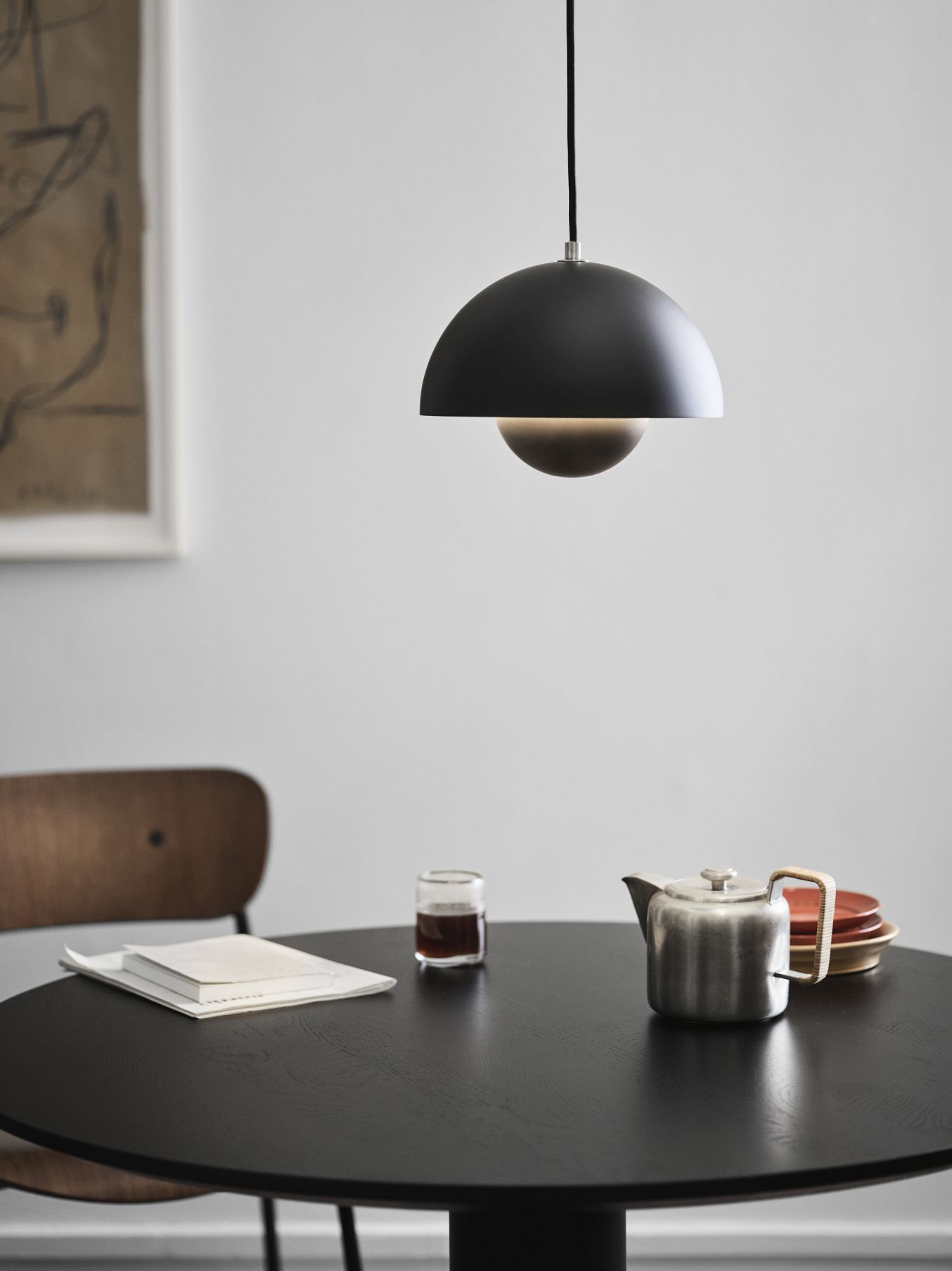 Schwarze VP1 Flowerpot Pendelleuchte von AndTradition über einem Esstisch mit Teekanne und Geschirr.