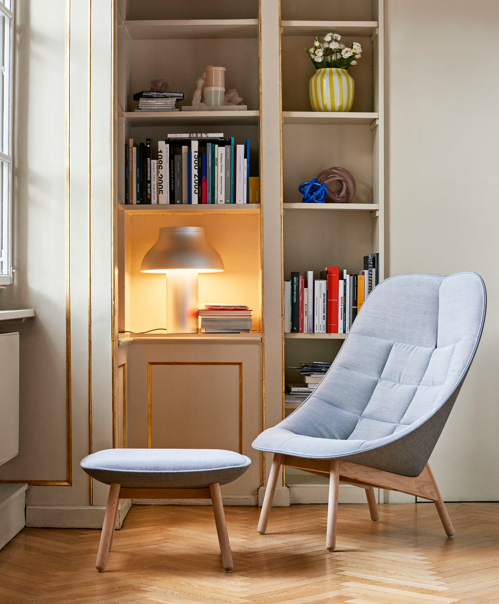Heller Uchiwa Quilt Sessel von Hay mit passendem Hocker vor Bücherregal. Moderner skandinavischer Sessel mit Holzbeinen.