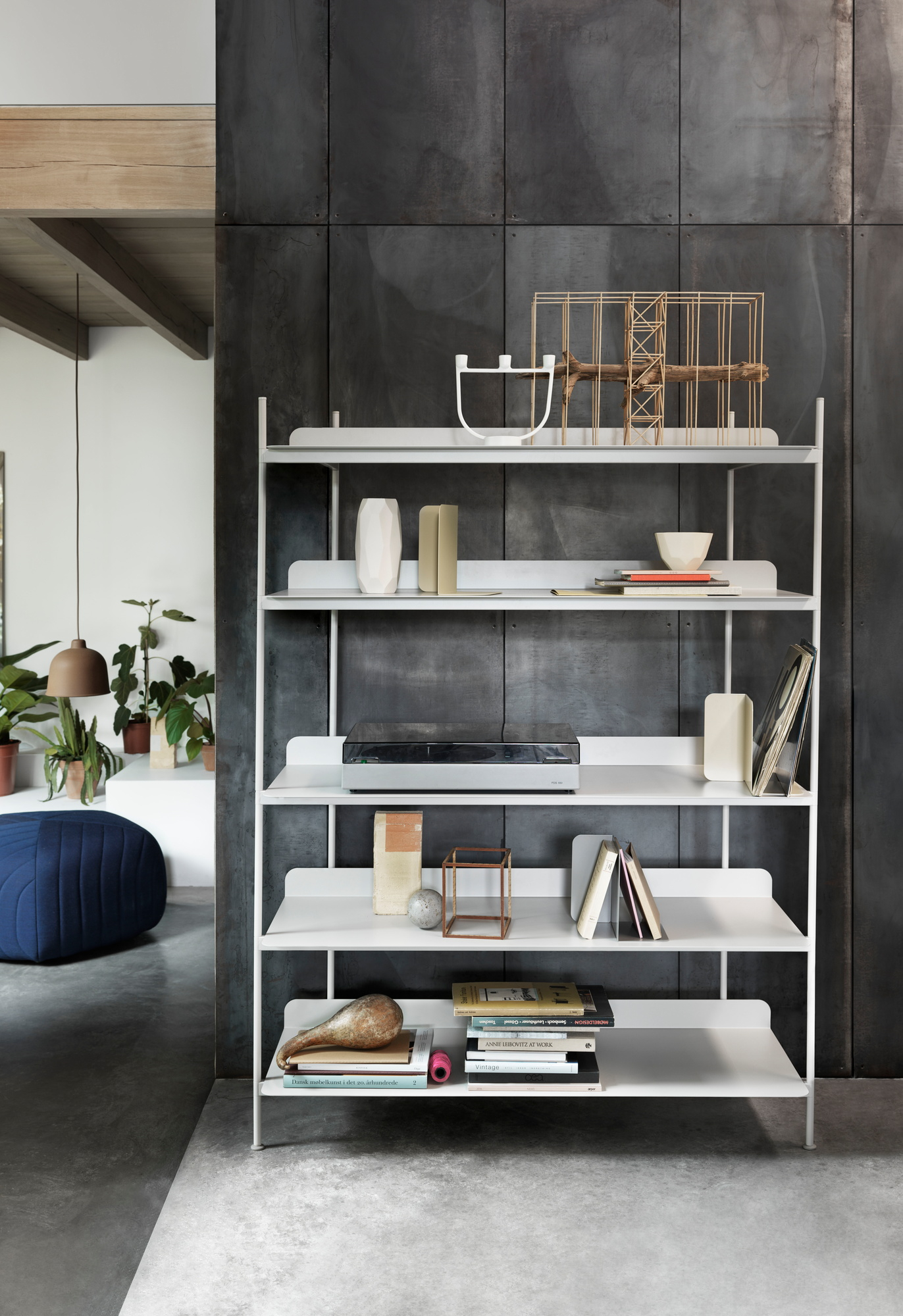 Muuto Compile Regalsystem in Weiß, verschiedene Höhen, dekoriert mit Büchern und Deko-Objekten vor dunkler Wand.