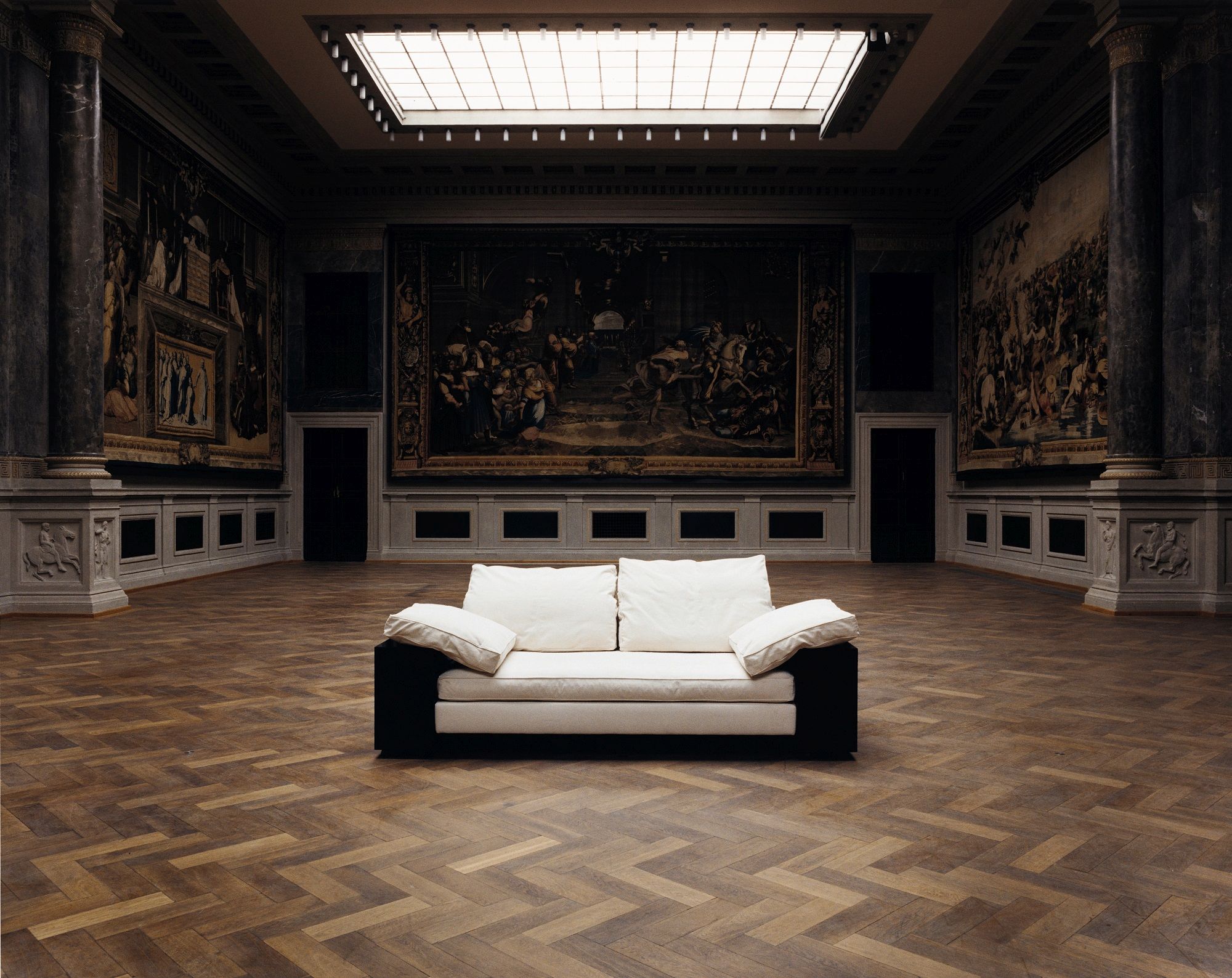 Lota Sofa von Classicon, modernes Design-Sofa mit weißen Kissen und dunklem Rahmen in großem Raum.