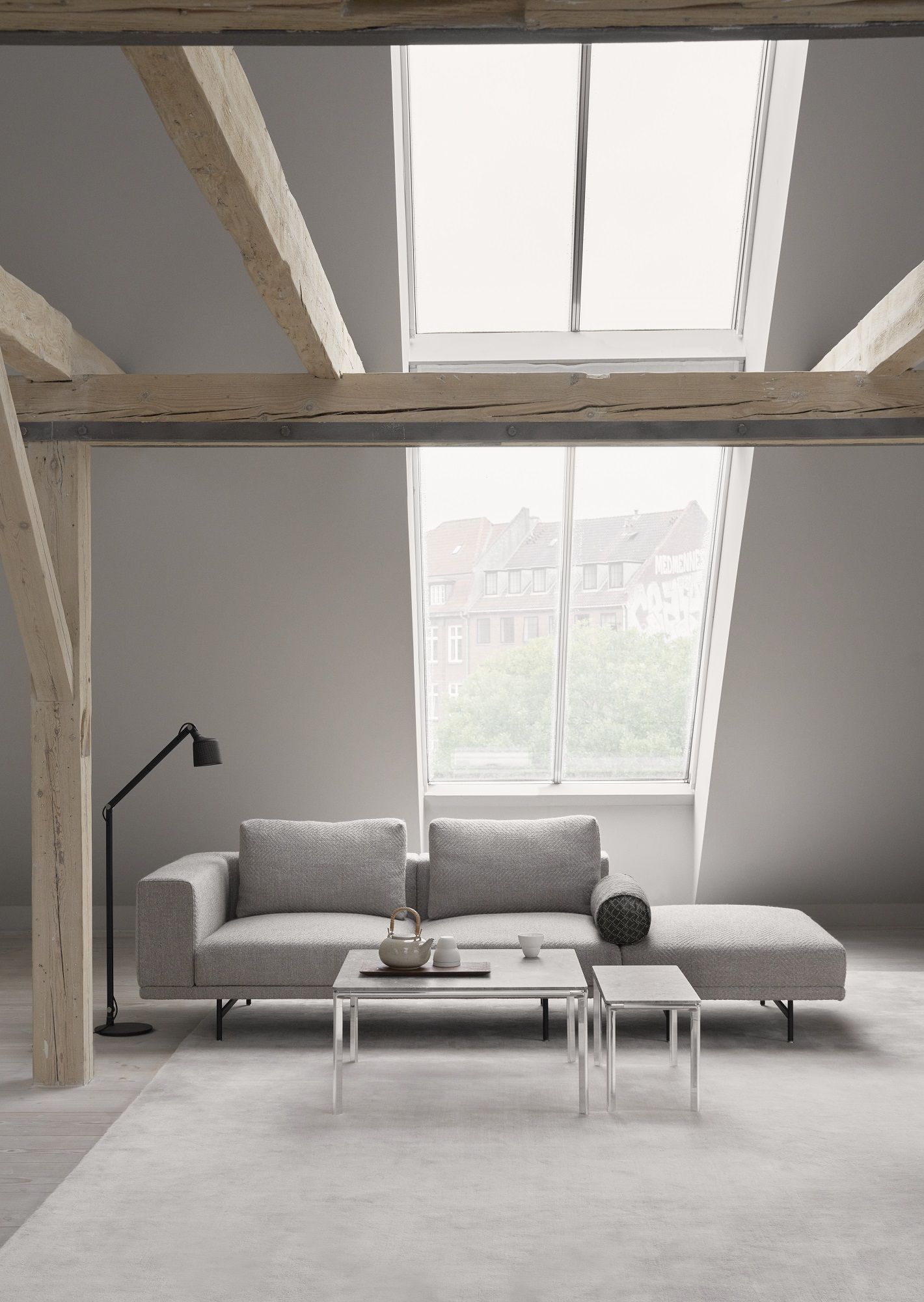 Vipp Couchtisch Square im modernen Wohnzimmer mit grauem Sofa und Dachfenster.