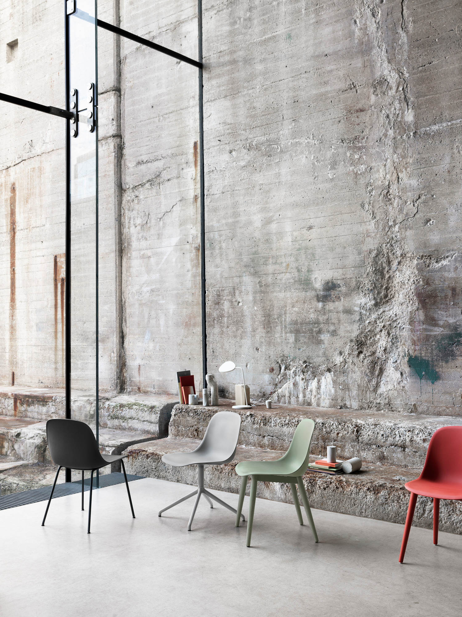 Mehrere Fiber Side Chairs von Muuto in verschiedenen Farben vor einer Betonwand.