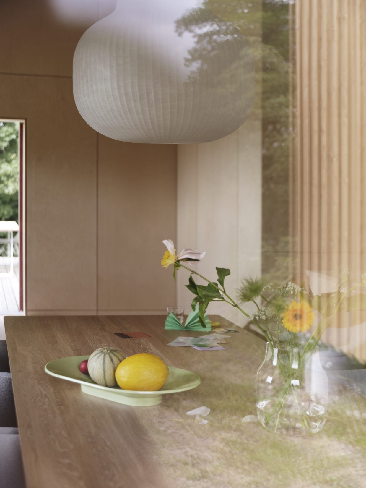 Detailaufnahme eines Muuto Fiber Soft Armchair Armlehnstuhls an einem Esstisch mit Dekoration und Lampe.