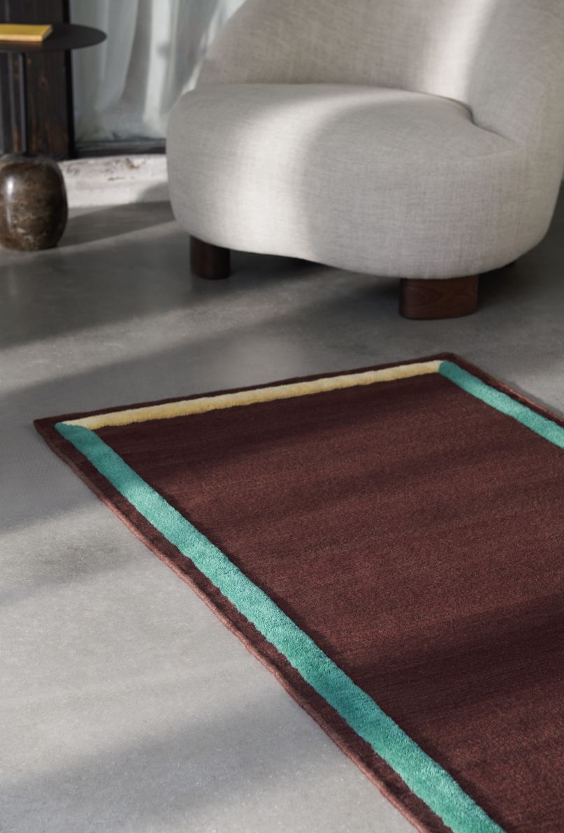 Detailaufnahme: Margas Loungesessel LC1 AndTradition mit braunem Teppich und farbigen Akzenten im modernen Wohnzimmer.