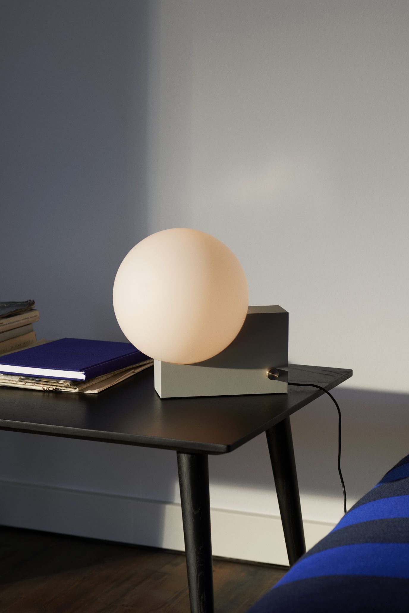 AndTradition In Between Table SK23 Couchtisch aus Holz, schwarz, mit Büchern und Lampe.