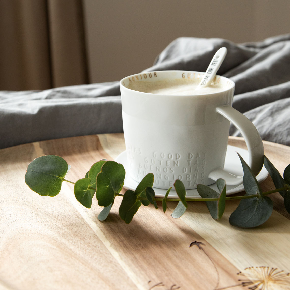 Räder Guten Appetit Tasse mit Kaffee und Löffel auf Holztablett mit Eukalyptus-Zweig.