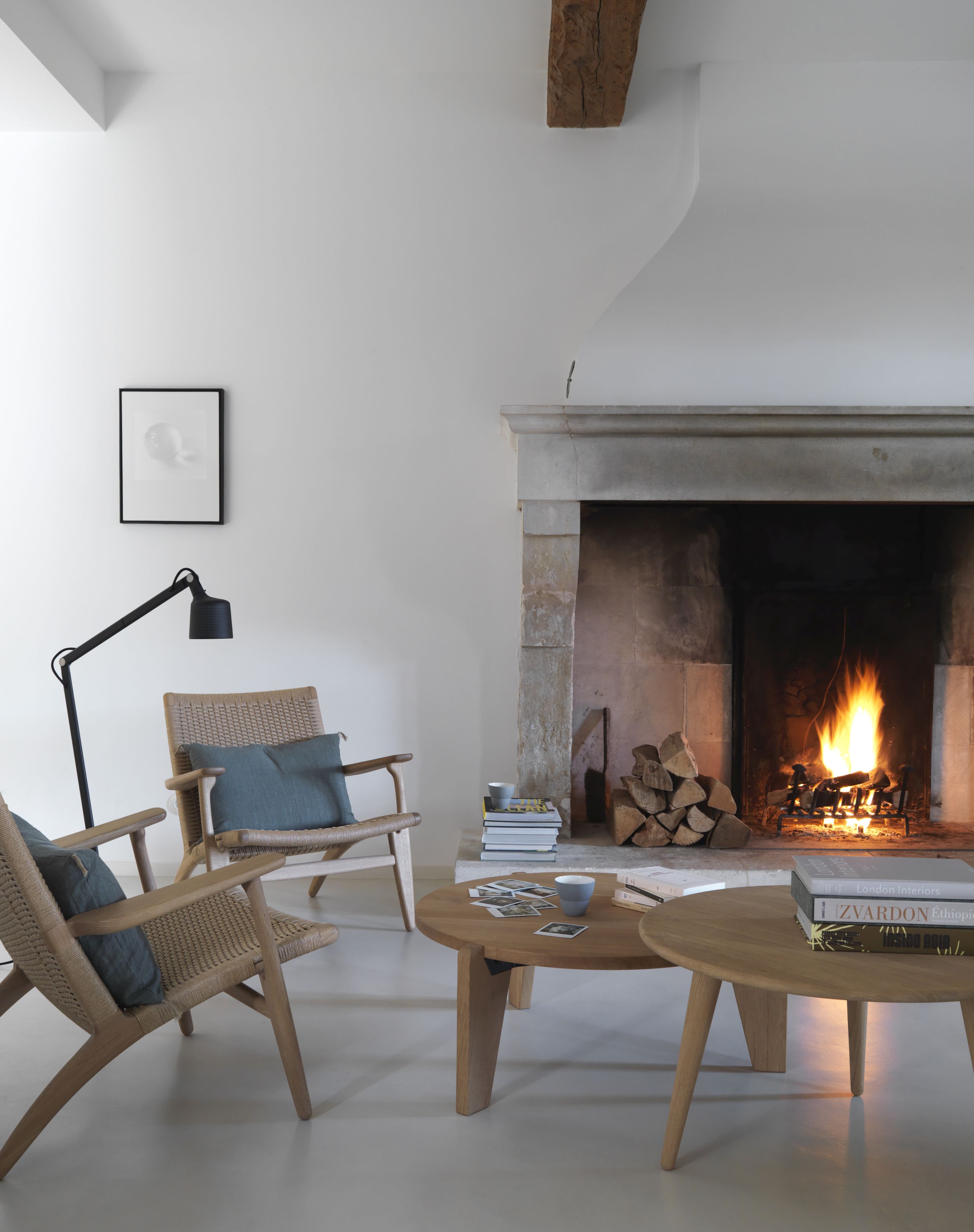 Helle Wohnzimmer Szene mit Vipp Boden Leselampe, Kaminfeuer, Korbsesseln und Holztischen für gemütliche Atmosphäre.