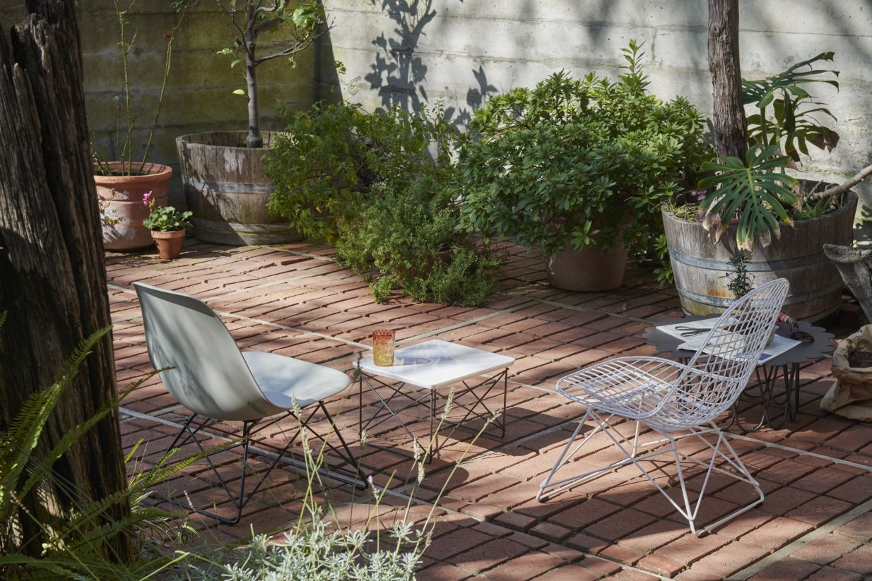 Eames Plastic Side Chair LSR Stuhl von Vitra in Grau und Weiß im Garten.