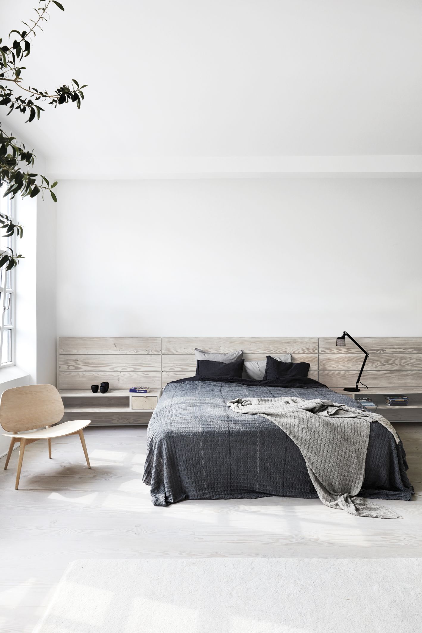 Schlafzimmer Interieur mit Bett, Holzstuhl und Vipp Tischleuchte auf Nachttisch für stimmungsvolle Beleuchtung.