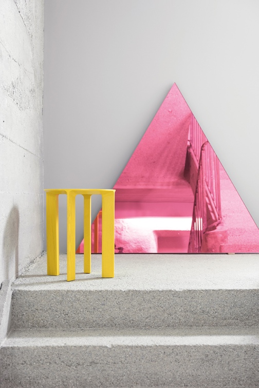 Gelber Hans Hocker von Schönbuch auf einer Betontreppe, im Hintergrund ein pinkes, dreieckiges Dekoelement.